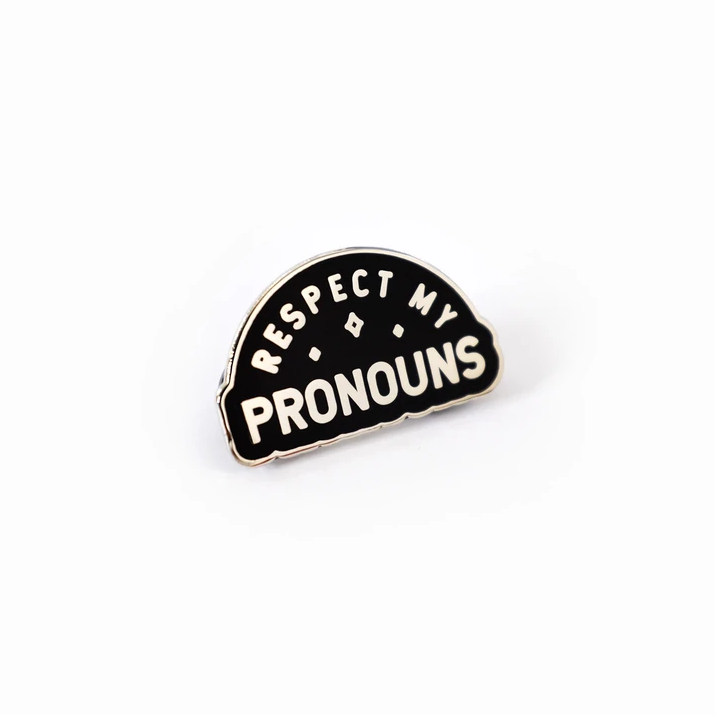 Semi-circle shaped enamel pin that reads 